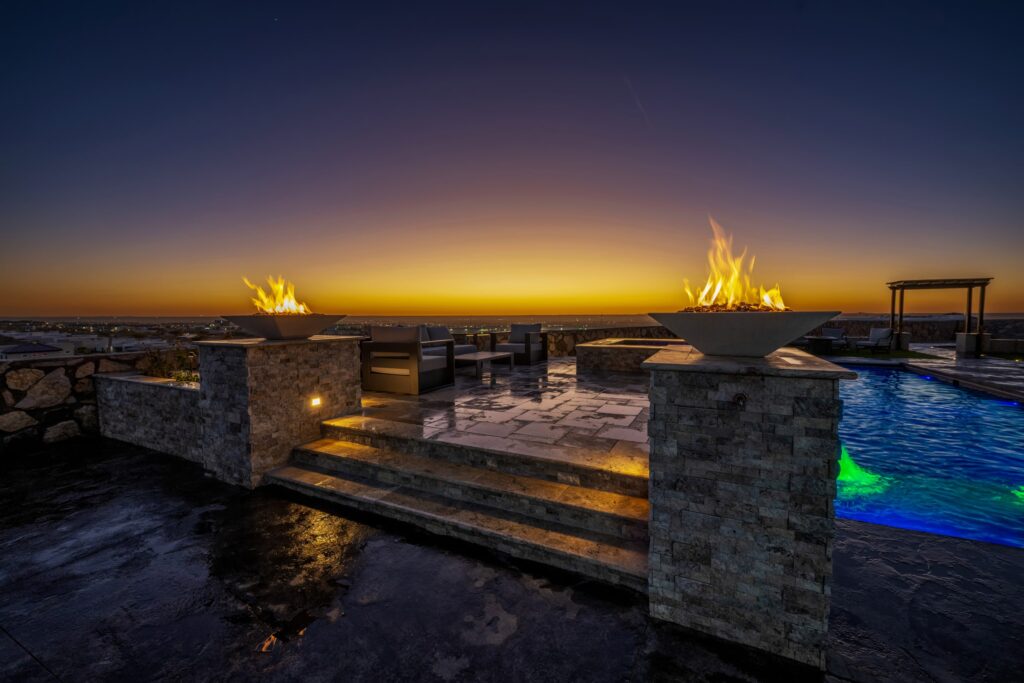 Elevated patio with fire features overlooking a custom pool at sunset in El Paso, TX