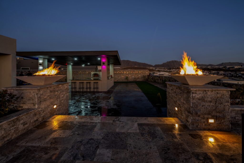 Fire bowl features and covered outdoor kitchen in a custom backyard by Eraland’s Custom Pools in El Paso, TX