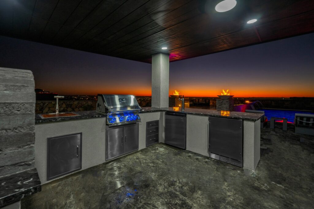 Custom outdoor kitchen with built-in grill and pool view in an El Paso backyard