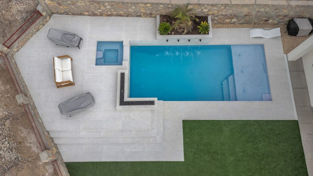 Top-down view showing the geometric pool and attached spa with clean concrete decking at this Eraland’s Custom Pools project in El Paso, TX.