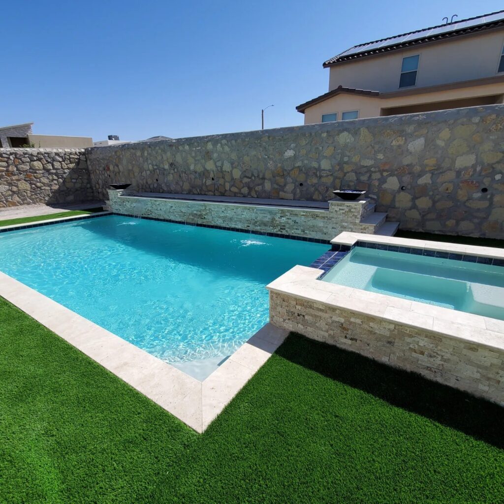 Custom pool and raised spa set against a natural stone privacy wall, part of an Eraland’s Custom Pools backyard design in El Paso, TX.
