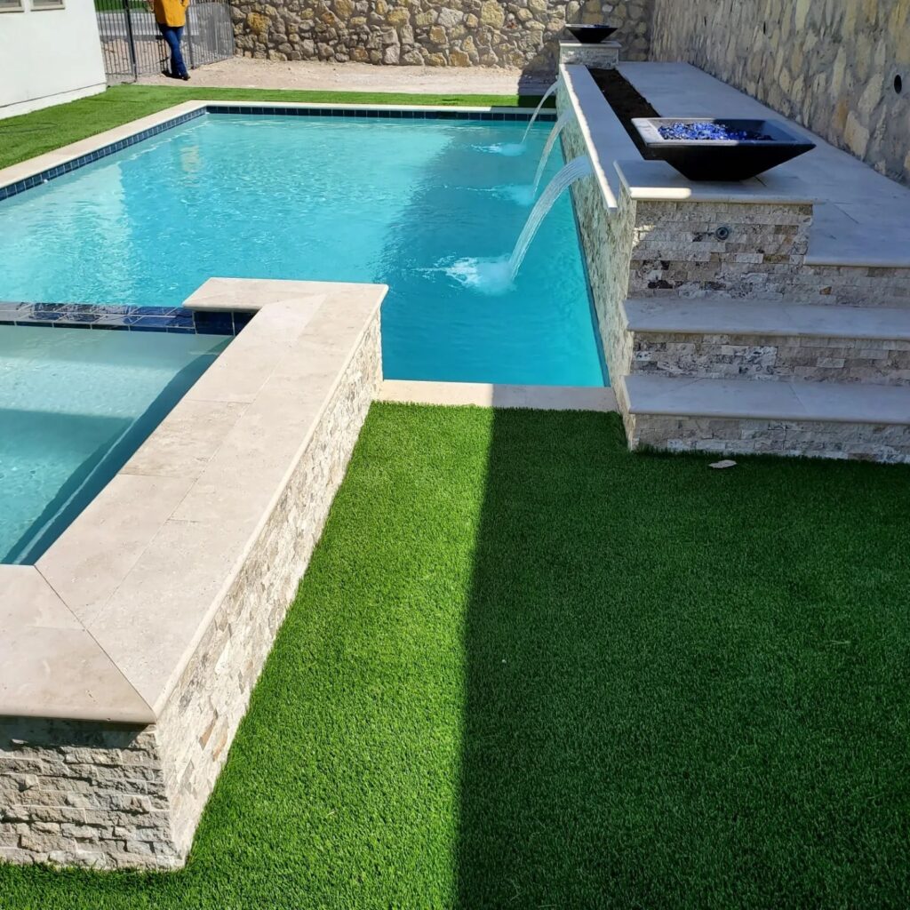 Close-up of wide spillway water features flowing into a custom pool, designed by Eraland’s Custom Pools in El Paso, TX.